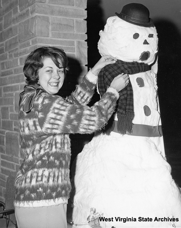 Woman putting scarf on snowman at Alpine Festival in Tucker County, n. d. Dave Cruise, photographer. Cabinet File, West Virginia State Archives  (Festival Alpine 004)