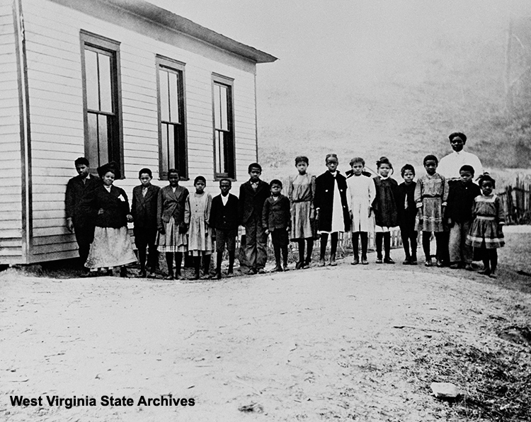 Black one-room school at Campbell's Creek, circa 1908. Left to right Arthur Price, Ione Webster, Hal Isaac, next seven unidentified, Ethel Brown, Minnie Cooper, unidentified, Elizabeth Webster, unidentified and Ethel Webster. Miss Mary Jones, their teacher, stands behind to the right. Anna Evans Gilmer Collection, West Virginia State Archives (012406)