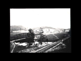 View of Richlands above the railroad bridge. Buildings visible in the distance, bridge and railroad tracks in the foreground.