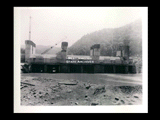 Dam during the hydroelectric power construction on the New River. Upstream view of sluice section. Racks are in place and water is starting to run through sluices. Temporary construction track is shown in place over sluice racks. New-Kanawha Power Company, Hawks Nest - Gauley Junction Development No. 254.