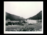 Dam during the hydroelectric power construction on the New River. Cofferdam is being extended to include blocks 20 and 21. Foundations for blocks 18 and 19 are completed inside of cofferdam where shovel is located. New-Kanawha Power Company, Hawks Nest - Gauley Junction Development No. 256.