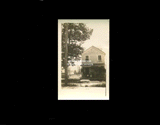 Two-story house with woman and child on the porch. From small red photo album.