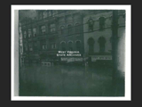 View in the 1400 block of Market Street in Wheeling during the 1936 flood. Signs include Rubin Brothers, State Auto Supply, and Hotel Colonial.