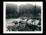 Dam site during the hydroelectric power construction on the New River. View showing piers being poured above crest of dam and excavation for west abutment flooded out temporarily. Construction bridge across river is shown topped by flood water. New-Kanawha Power Company, Hawks Nest - Gauley Junction Development No. 213.