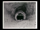 View into tunnel during the hydroelectric power construction on the New River. View shows tunnel roughly excavated to 32 foot diameter in sandstone. Walls have been partially trimmed and invert blasted but not excavated. Note downstream portal approximately 6,900 feet in distance. Camera at Station 104 + 00. New-Kanawha Power Company, Hawks Nest - Gauley Junction Development No. 330.