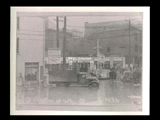 Flood scene in 1936 at Chapline and 16th streets. Truck at service station. Signs include Atlantic White Flash American Tire Repair Works, Mohawk Tires, R. B. Rutan Transfer.