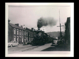 Baltimore and Ohio train on 17th Street in Wheeling with coal cars. Automobiles at curbside.