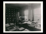 Interior view of Ohio Valley Hospital showing the record room with a man and woman sitting at desks and filing cabinets along the wall.