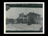 Winter view of store and other frame buildings across railroad tracks in May, West Virginia.