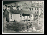 White school at mine Number 253, Thelma Number 6 at Six. House on the hillside in the background. Three men are at fence in foreground. This picture is also found in the DeHaven Collection, Roll 1599 02.