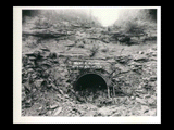 Tunnel portal and intake at dam during the hydroelectric power construction on the New River. Men working in front. Heading is approximately 16 feet. New-Kanawha Power Company, Hawks Nest - Gauley Junction Development No. 114.