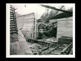 Dam site during the hydroelectric power construction on the New River. Completed upstream and downstream retaining walls and recess for east abutment shown. Forms shown are built for concreting east abutment to Elevation 733.25. Block No. 1 of the dam shown in foreground and east abutment are concreted to Elevation 768.00 at present. New-Kanawha Power Company, Hawks Nest - Gauley Junction Development No. 235.