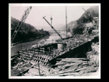 Power house during the hydroelectric power construction on the New River. View looking downstream showing walls concreted to generator floor elevation for all units and formwork complete for concreting generator foundation to Elevation 690.0 in Unit No. 4 and generator floor in Unit No. 5. Bridge across New River in the distance. New- Kanawha Power Company, Hawks Nest - Gauley Junction Development No. 289.