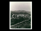 Company town and railroad tracks. Hillside view of houses with tracks at bottom and automobiles on a road. This is a partial of another <MR=picture;CL07-0010;FOTO> in the collection.