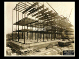 Girder structure on Building 2 (East Wing) during construction of the Cass Gilbert WV State Capitol building. A railroad car is at right.