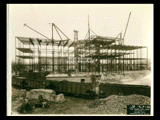 Ground level stonework on Building 2 (East Wing) during construction of the Cass Gilbert WV State Capitol building. Girder structure is visible. Building 1 is visible behind the girder. Railroad cars are in the foreground.