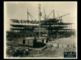 Ground level stonework on Building 2 (East Wing) during construction of the Cass Gilbert WV State Capitol building. Girder work is visible. Railroad car in the foreground.