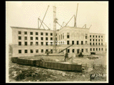 Fourth level stonework on Building 2 (East Wing) complete during construction of the Cass Gilbert WV State Capitol building. Railroad cars in the foreground.