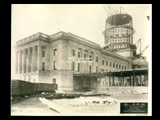 Walkway and connector between Main Building and Building 1 (East Wing) during construction of the Cass Gilbert WV State Capitol building. Railroad cars at left. Girders of dome visible.