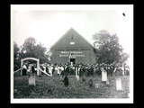 Group outside the Broad Run Baptist Church. Large group of men, women, and children outside a two-story brick building with Gothic style window. Cemetery markers in the foreground.