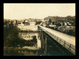 View of Haywood looking past bridge. Martin Brothers Company, railroad cars.