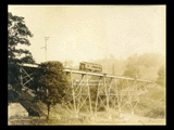 Streetcar on Hepzibah viaduct with road and fence below.