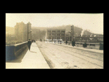 View across bridge of Monongahela Valley Traction Company station and other buildings in Clarksburg. People on bridge. [Loar and] White Clarksburg Best Clothiers sign.