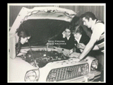 Three students being instructed by a man in auto shop class at Mount de Chantal Visitation Academy in Wheeling. Hood of automobile open. Students L-R: Jean Sivard, Ivy Antioch, Deborah McCulley.