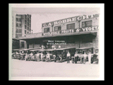 C. A. Robrecht Company Wholesale Fruits and Vegetables building. Trucks parked in front with workers standing. Pete Purpura at far right.