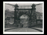 View across Wheeling Suspension Bridge. Horse and buggy on bridge. Sign for Logan Drug.