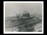 Riverside blast furnace with railroad cars alongside.
