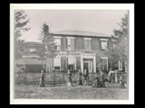 Two story buick house built by William McColloch with group of men, women, and children in yard.