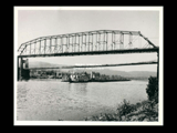 View of the steel bridge, suspension bridge and piers of the Fort Henry bridge over the Ohio River at Wheeling. Boat Charles S. Stevenson with barge.