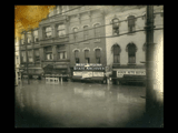 View of Wheeling during flood. Signs include State Auto Supply, Hotel Colonial, Rubin Brothers, Hollywood Grill, Coca Cola.