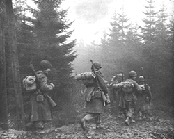 Men of the 325th Glider Infantry Regiment moving through fog to a new position, Belgium, December 1944. Once glider crew members disembarked on the ground, they became infantrymen. Photo shows them during the Battle of the Bulge. Courtesy U.S. Army Center of Military History